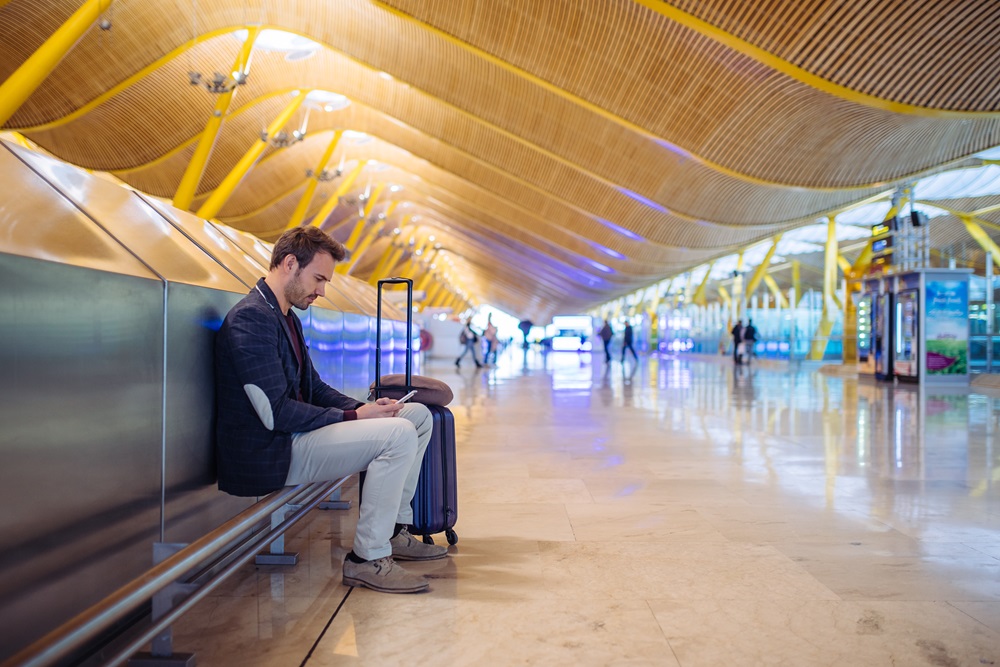 young man waiting and using mobile phone at the airport Business traveler on layover in the airport using cell phone