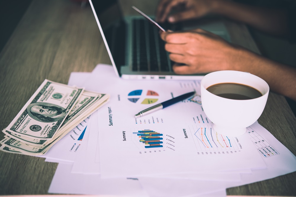 Working place of trader. The table covered by cash notes, keyboa Finance team analyzing business travel expenses with a cup of coffee