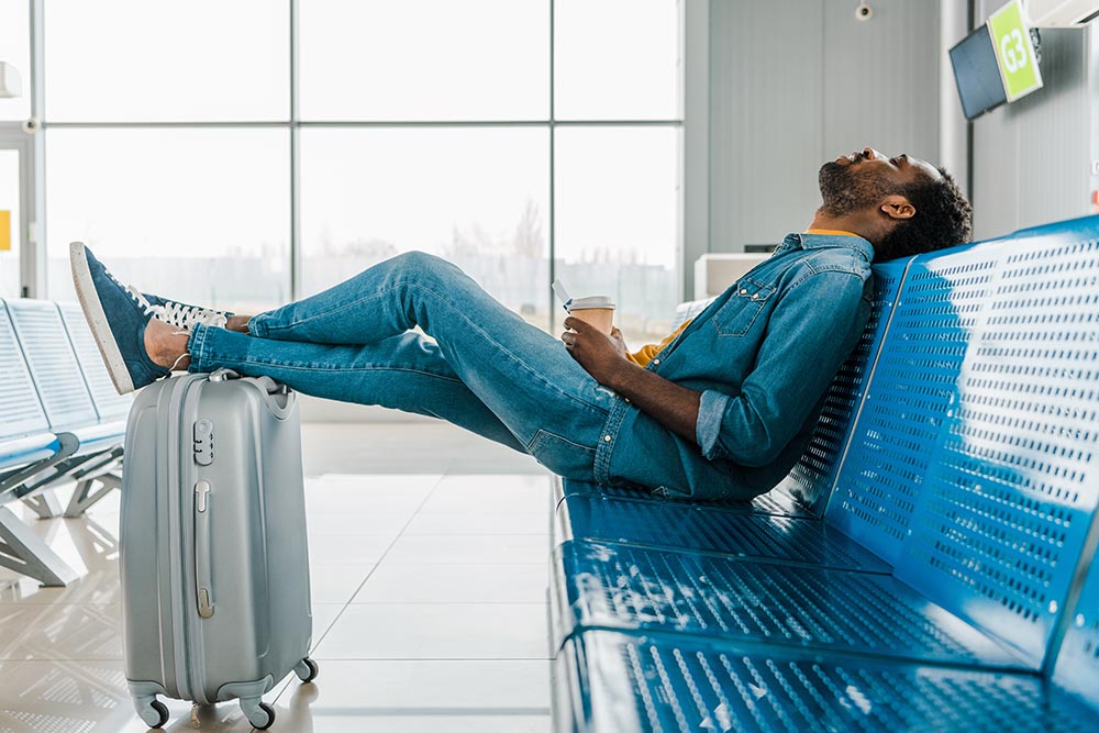 african american man sleeping in airport with coffee to go and l Entschädigung