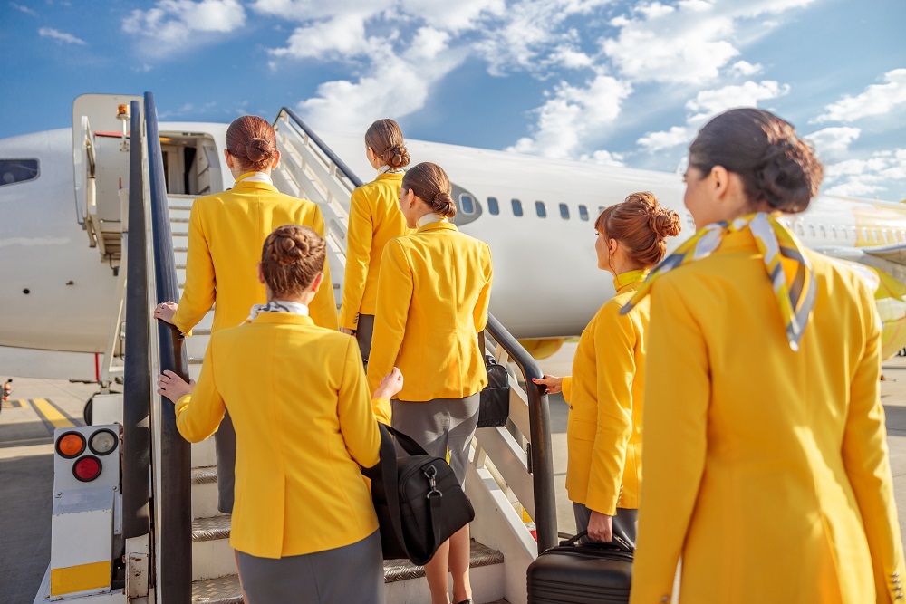 Stewardess standing on airplane stairs under cloudy sky fluege de billig