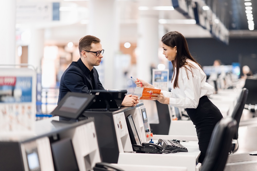 handsome businessman handing over air ticket at airline check in counter Flugreisen