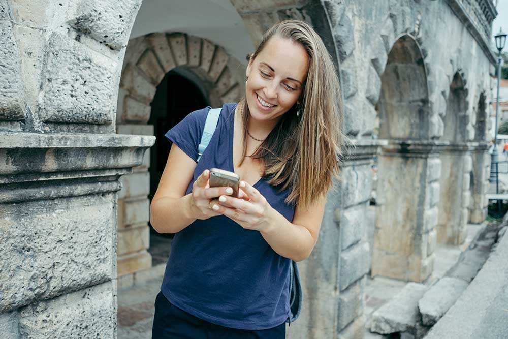 Young woman traveler in a blue T-shirt with backpack looking at Reisender im Bahnhof wartet mit Gepäck auf den Zug