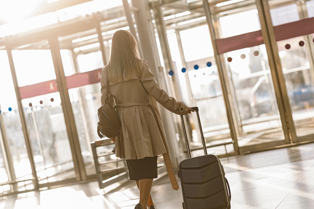 Female traveler carrying trolley luggage bag at airport Flugreise-Thanksgiving