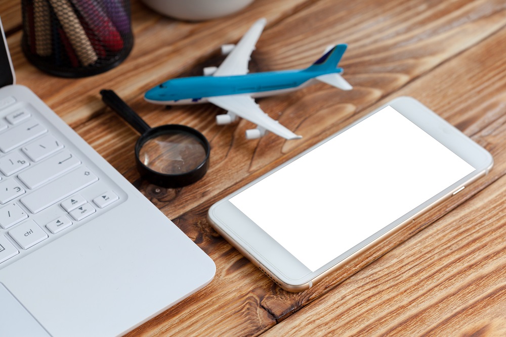 office desk with laptop smart phone and business office background. Ein Globus auf einem Laptop mit einem Spielzeugflugzeug