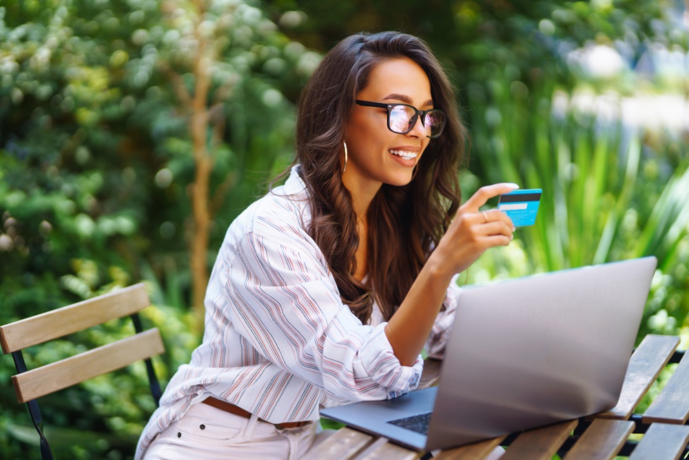 Geschäftsreisender bucht eine Reise mit einer Hotelkarte, während er mit einem Laptop in einem Café arbeitet