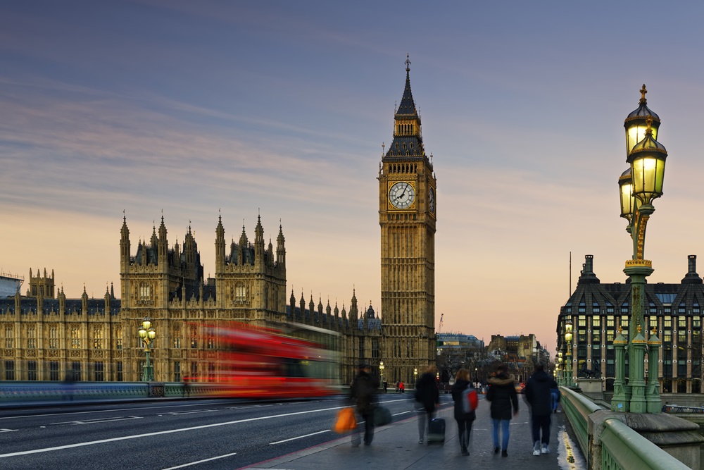 London Big Ben with business travelers walking and red bus in the distance