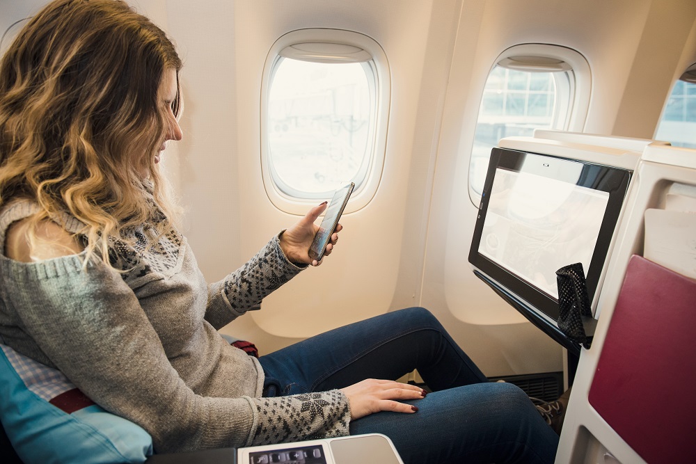Passenger in premium economy class of airplane with smartphone premium economy vs economy class