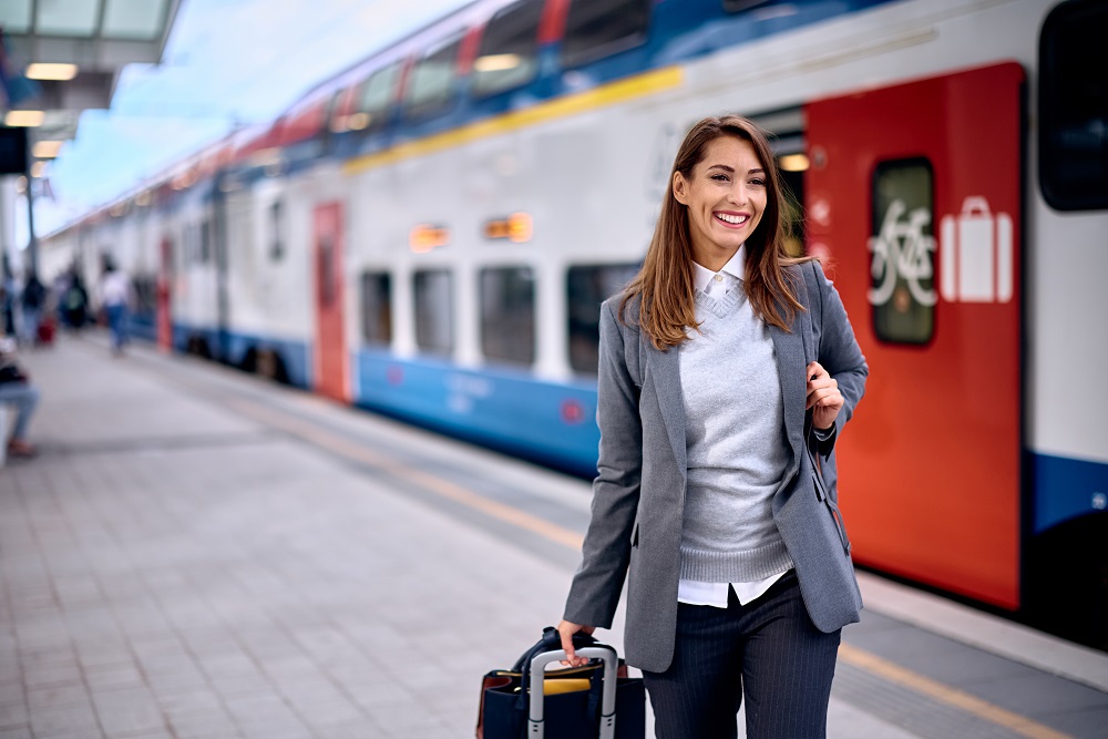 Young happy woman arriving at train station. reduce carbon footprint business travel