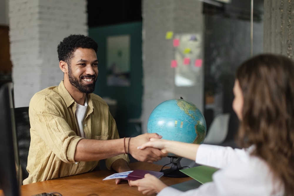 Young woman at job interview, shaking hands. Travel agent shaking hands and giving passports with tickets