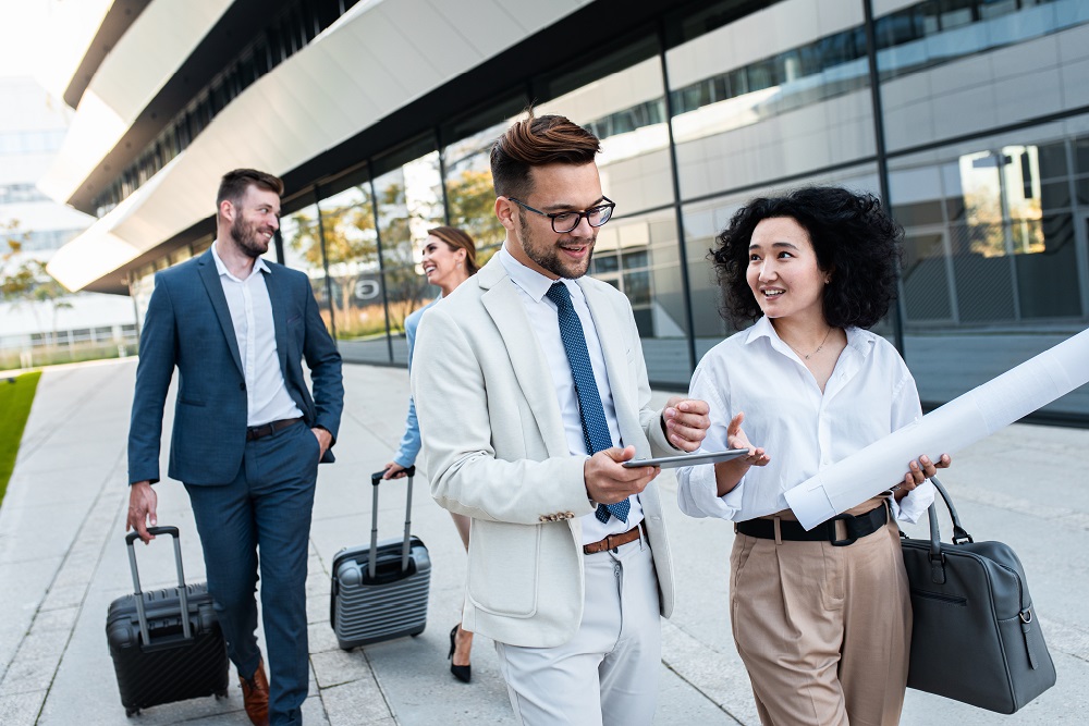 Group of coworkers walking outside in front of office buildings Group of coworkers on a business trip talking about a project outside the office