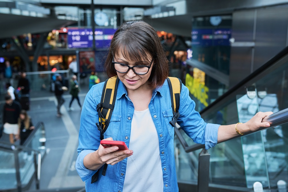 Woman on escalator stairs in building of city transport station with smartphone woman on escalator looking at cell phone corporate travel trends